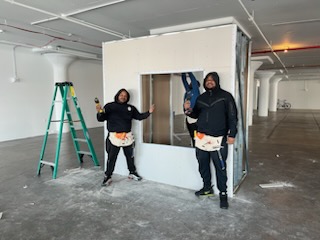 Black men in black clothes with work smocks installing drywall